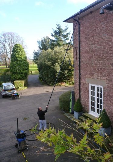 An image of a Ultimate Cleaning Solutions team member cleaning a gutter
