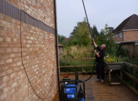 An image of a Ultimate Cleaning Solutions team member cleaning a gutter